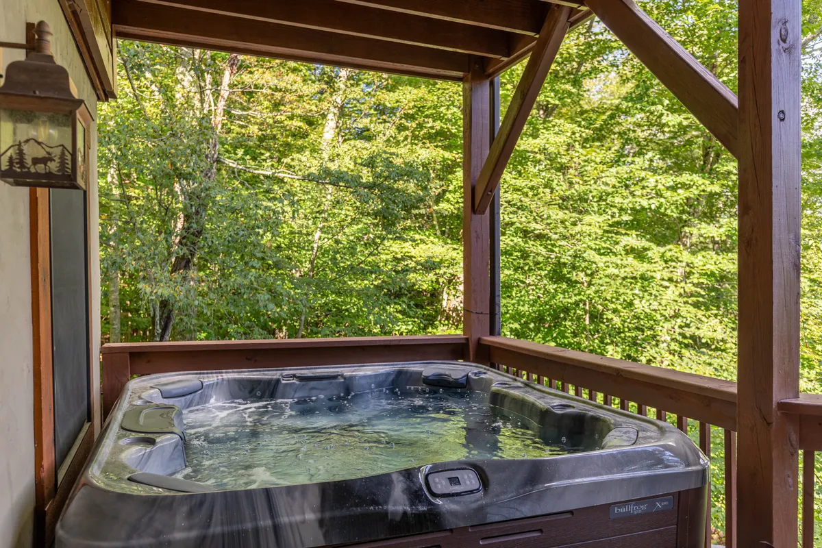 A private outdoor hot tub nestled beside a wooden structure and surrounded by greenery. The setting feels intimate and luxurious, ideal for couples looking to relax under the stars after a day of adventure.