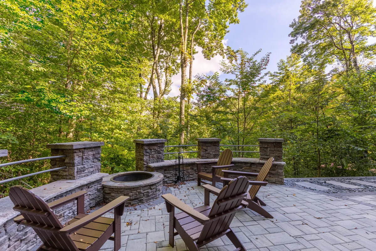 A welcoming fire pit encircled by a stone seating area, nestled among tall trees. The scene conveys an inviting spot for families to gather outdoors, share stories, and enjoy evenings under the stars.