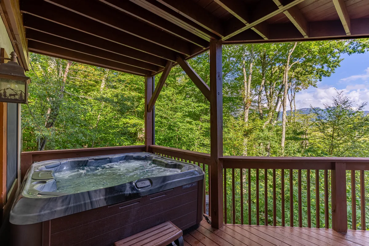 A luxurious hot tub set against a backdrop of trees and mountain views, with enough space for family or friends to gather. The tranquil setting invites relaxation after a day of adventure, with the promise of breathtaking sunsets or stargazing nights while soaking in the warmth.