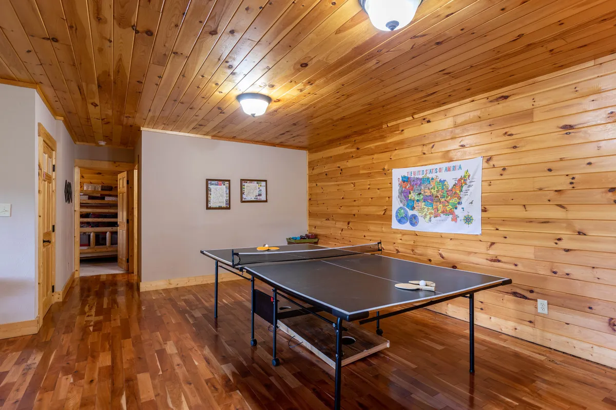 This image features a ping pong table as the focal point, surrounded by wood paneling and framed maps, all creating a playful and relaxed setting. The space is clearly designed for recreation and socializing, and the casual ambiance makes it perfect for gatherings and friendly tournaments.